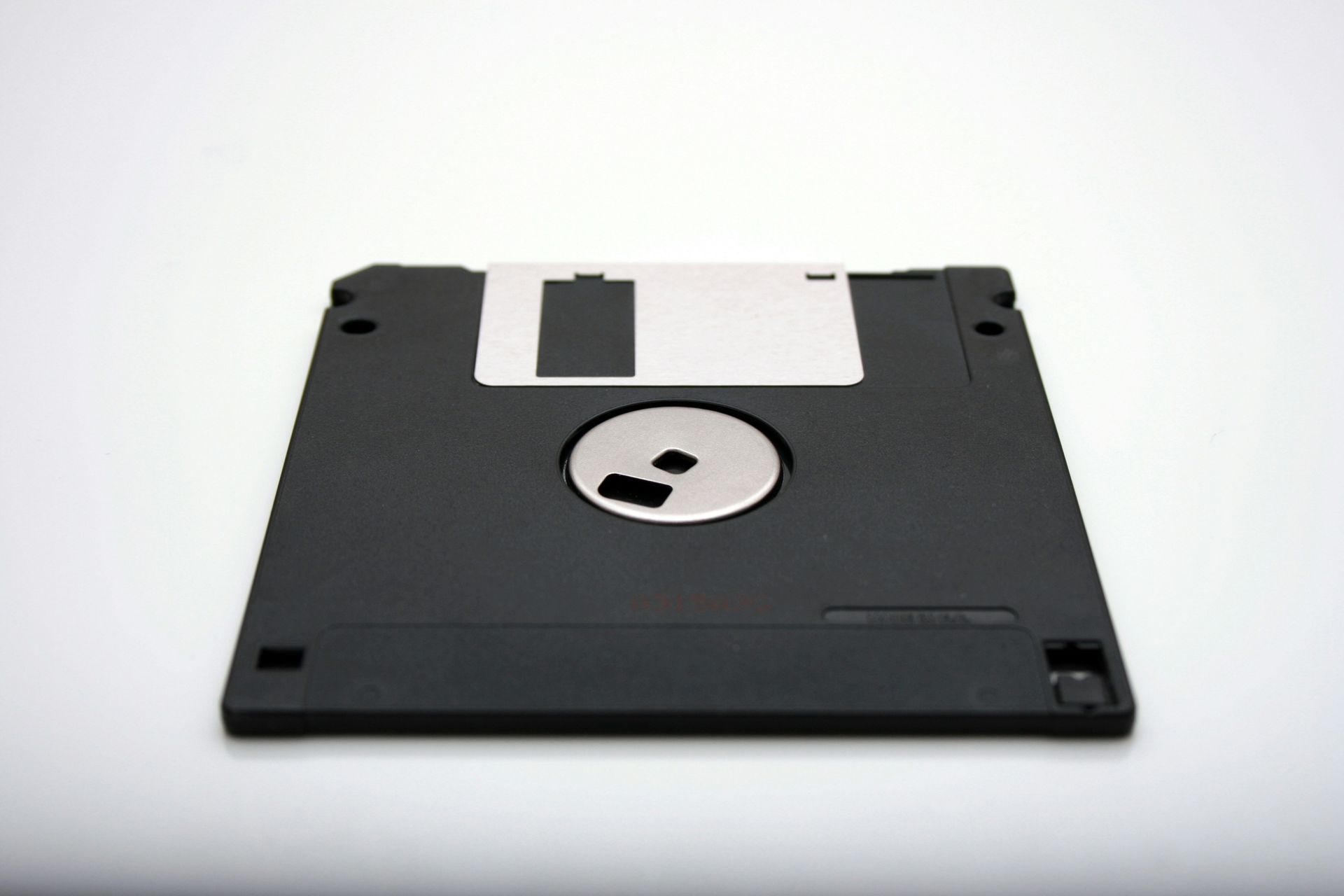 Black 3.5-inch floppy disk on a white background, the data storage device from the 80's.