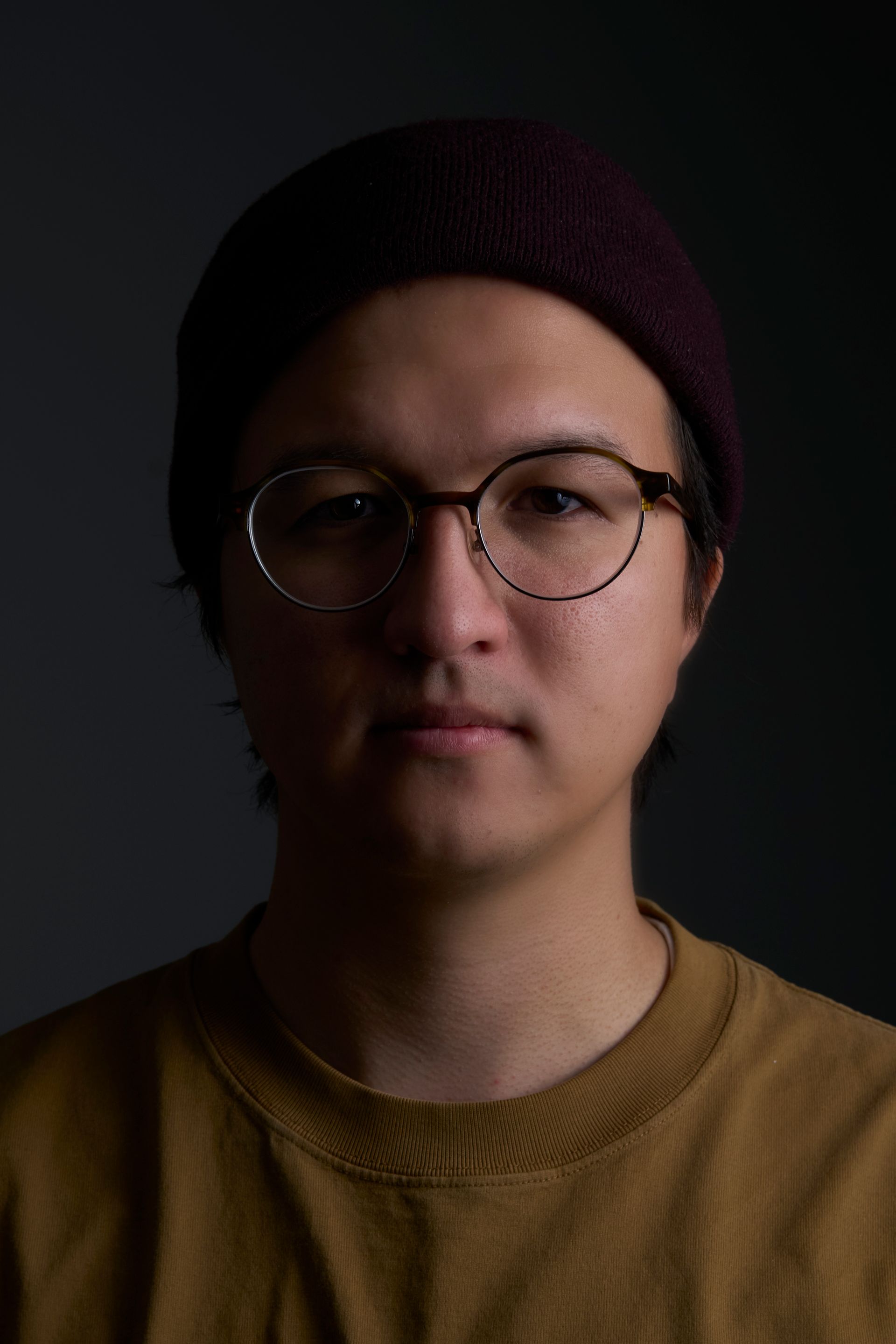 A man wearing glasses and a beanie is looking at the camera.