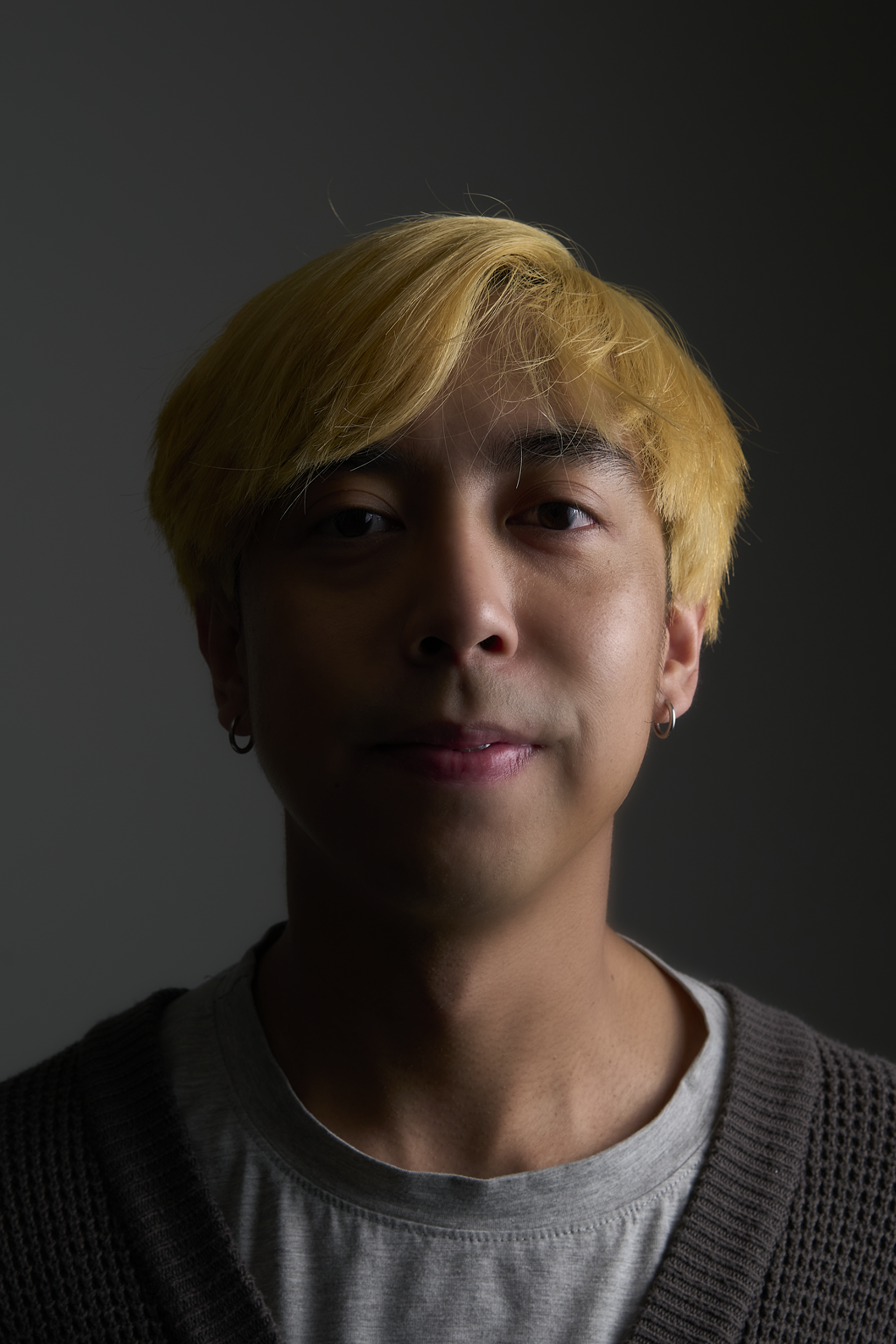 A man with blonde hair is looking at the camera in a dark room.