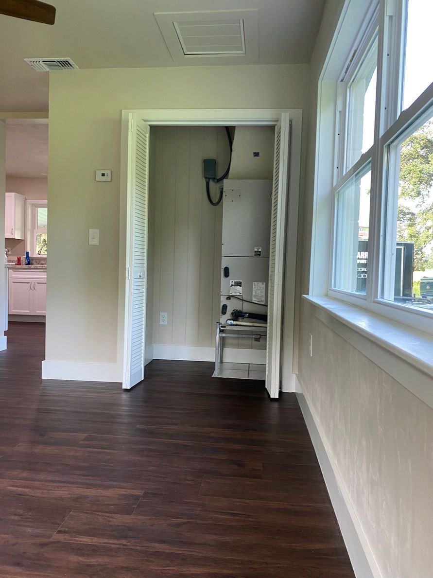 Interior of a room with dark wood floor, an appliance closet, and a window.
