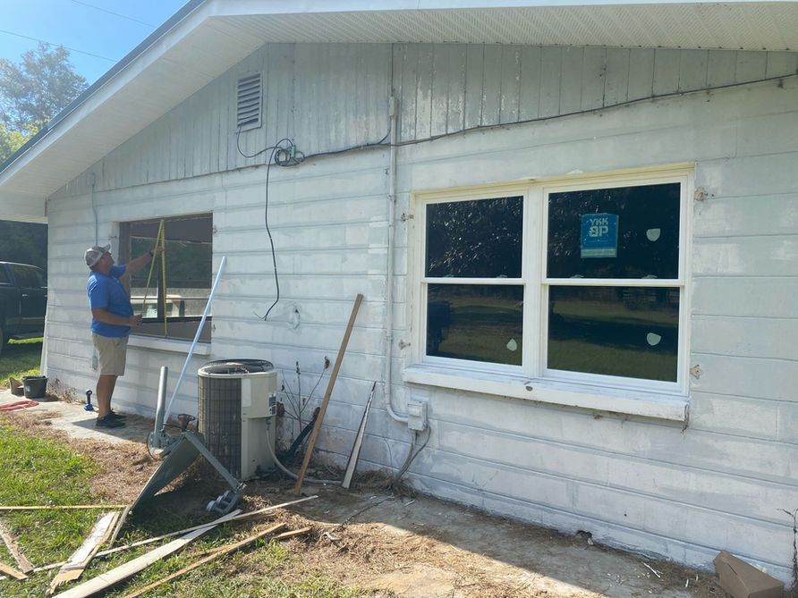 Man measures window frame on a white house, new window installed, work in progress, outdoors.