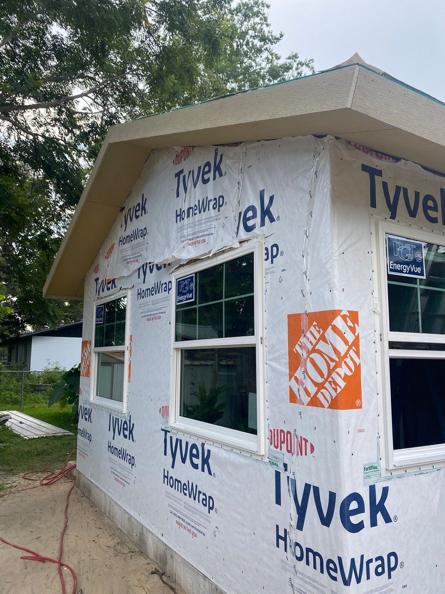 Small building under construction, covered in Tyvek wrap, with windows and Home Depot logo.