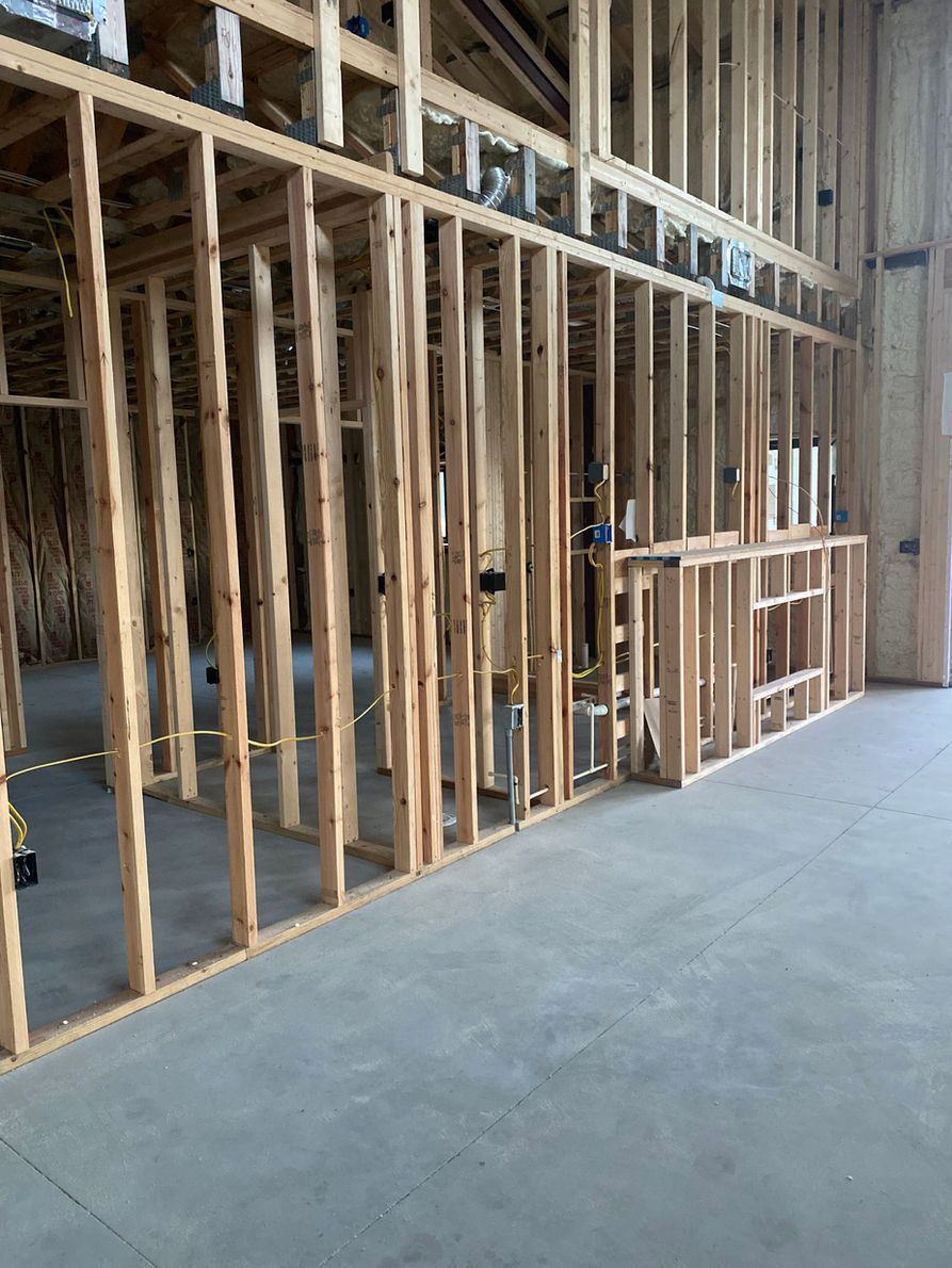 Interior view of a building under construction with wooden framing. Concrete floor.