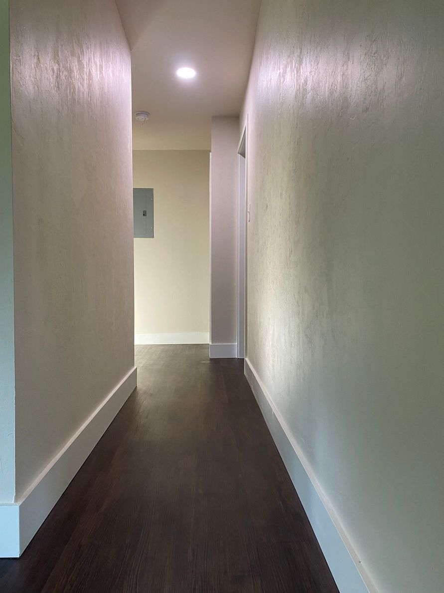 Narrow hallway with dark wood floor and white walls.