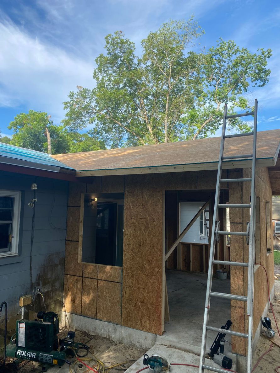 Exterior construction; a new addition to a building, with a ladder leaned against the side; sunny day.