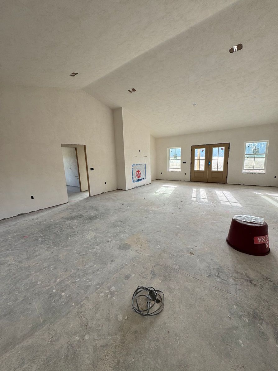 Construction site interior: empty room with concrete floor, white walls, door, and a red bucket.