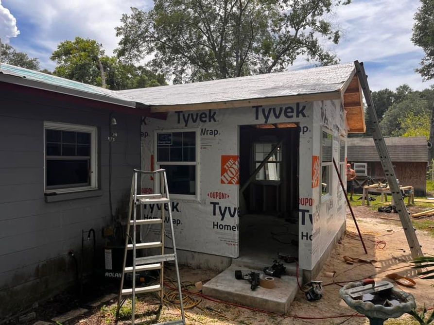 Construction site: a small addition wrapped in Tyvek siding is being built onto a house.