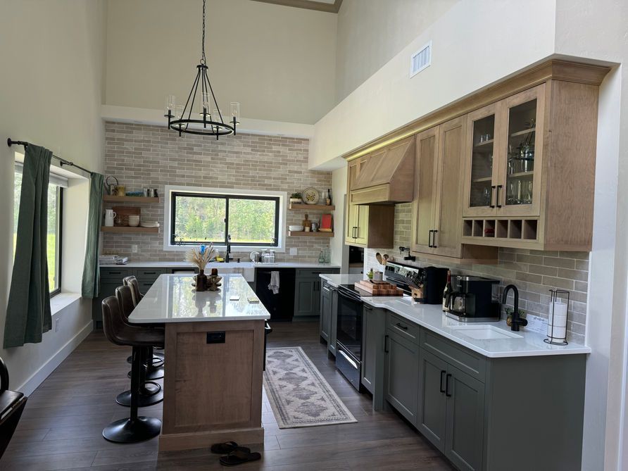 Kitchen with high ceilings, wood cabinets, island, and brick backsplash.