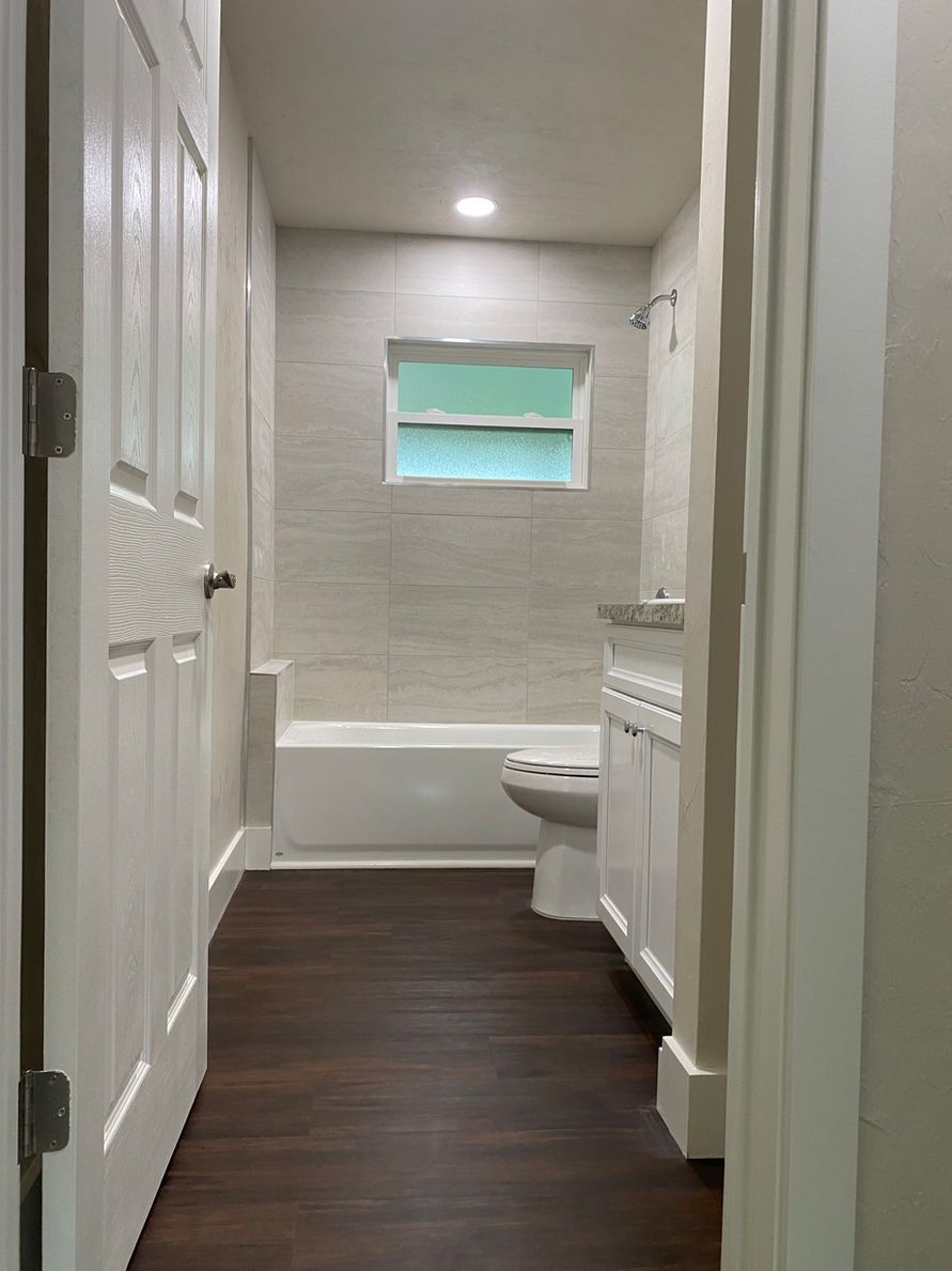 Bathroom with dark wood floor, white walls, and fixtures.