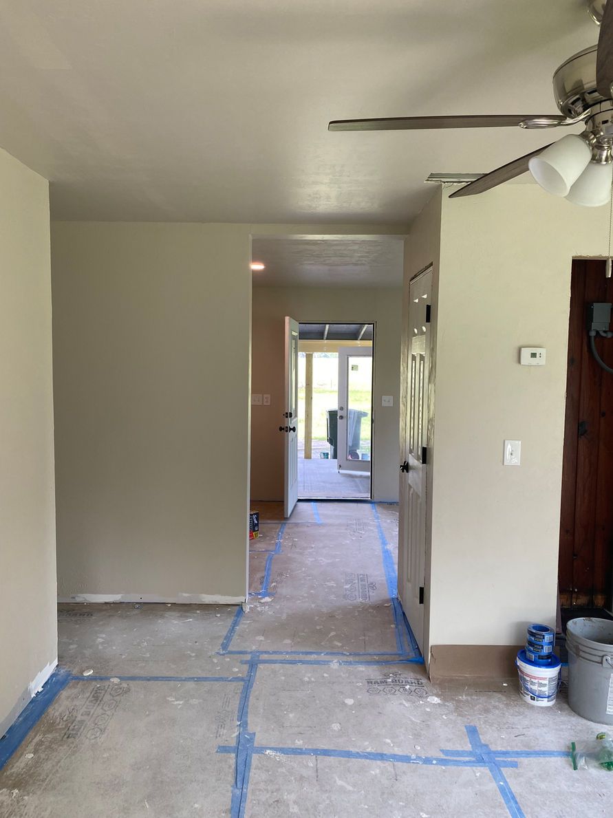 Interior view of a room with a hallway and doorways. Concrete floor, beige walls, and natural light.
