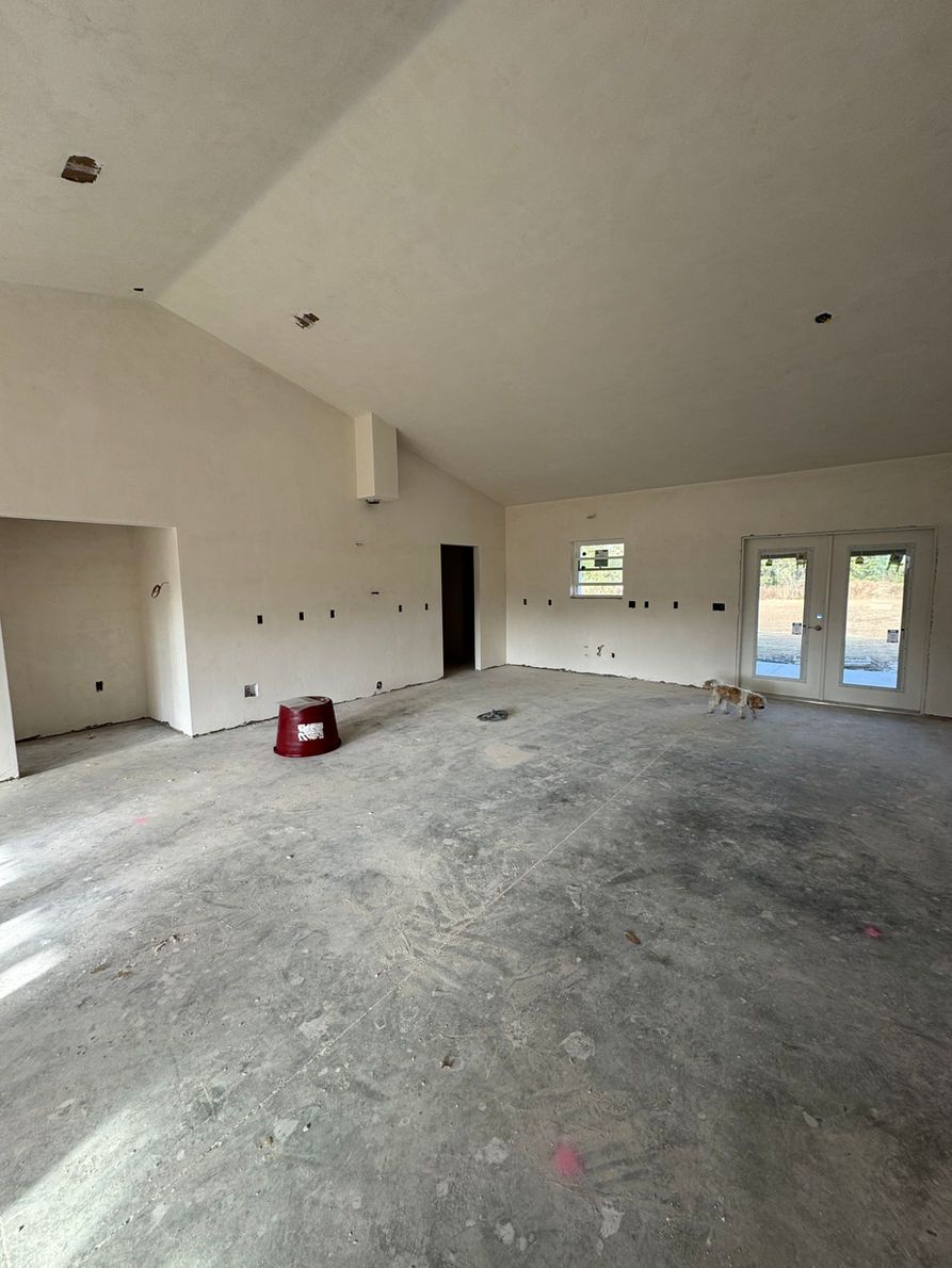 Interior of a room under construction, with unfinished walls, concrete floor, and light from windows.