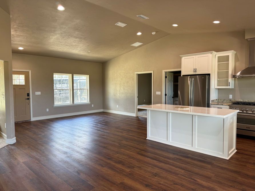 Open-concept living space with a kitchen island, stainless steel appliances, and wood-look flooring.
