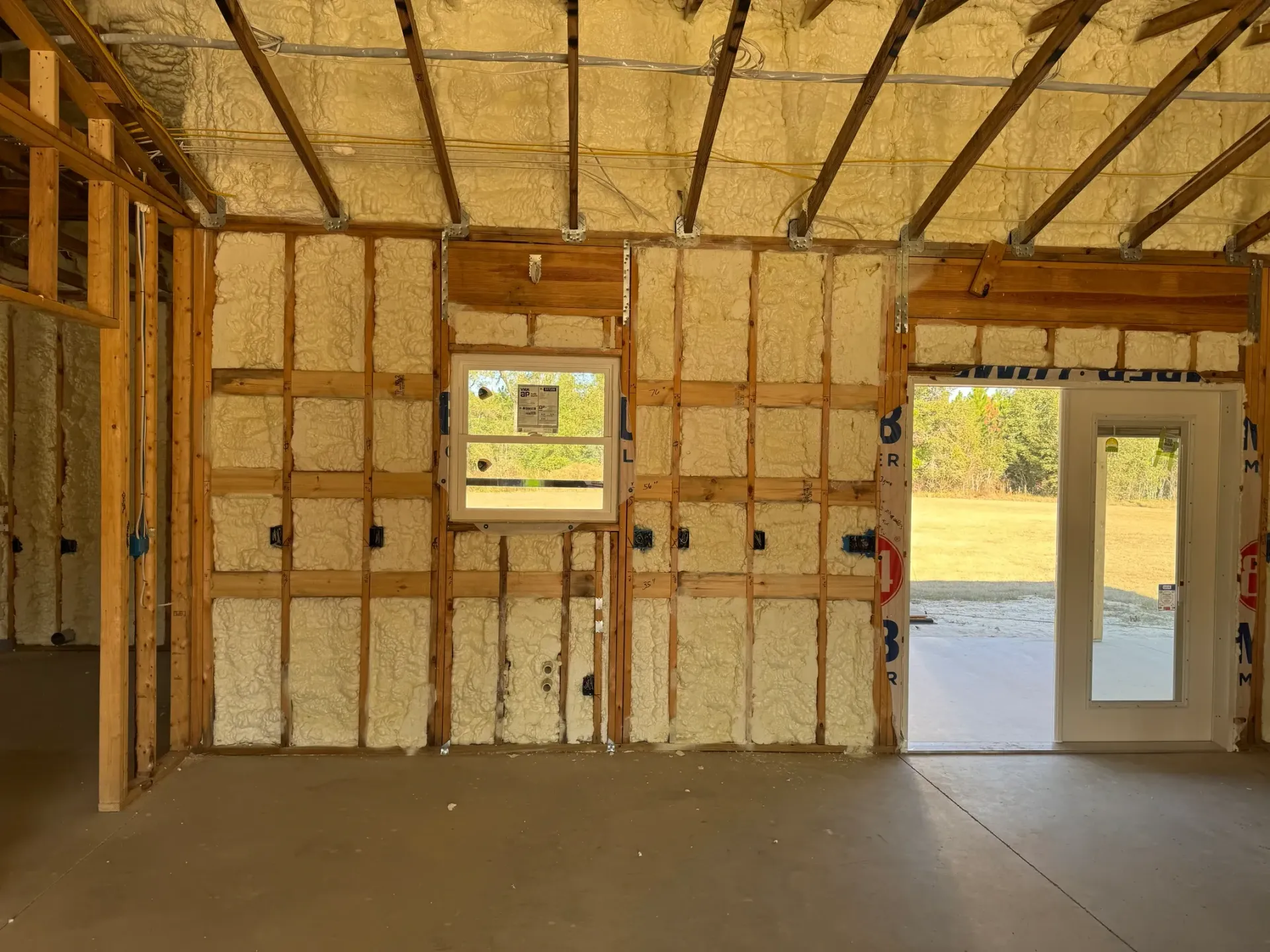 Interior view of a new house under construction. Walls and ceiling are insulated with yellow foam.