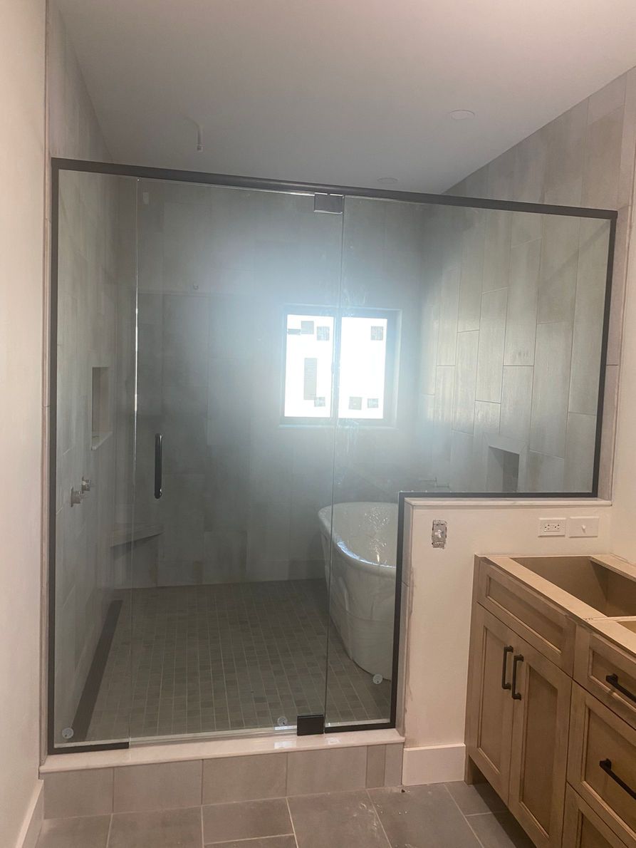 Bathroom with a glass shower enclosure, bathtub, and wooden vanity with open cabinets.