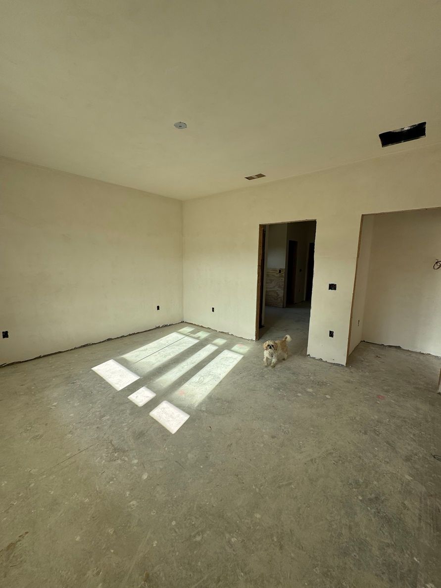 Empty room with unfinished walls and concrete floor. Sunlight streams through a window, illuminating the space.