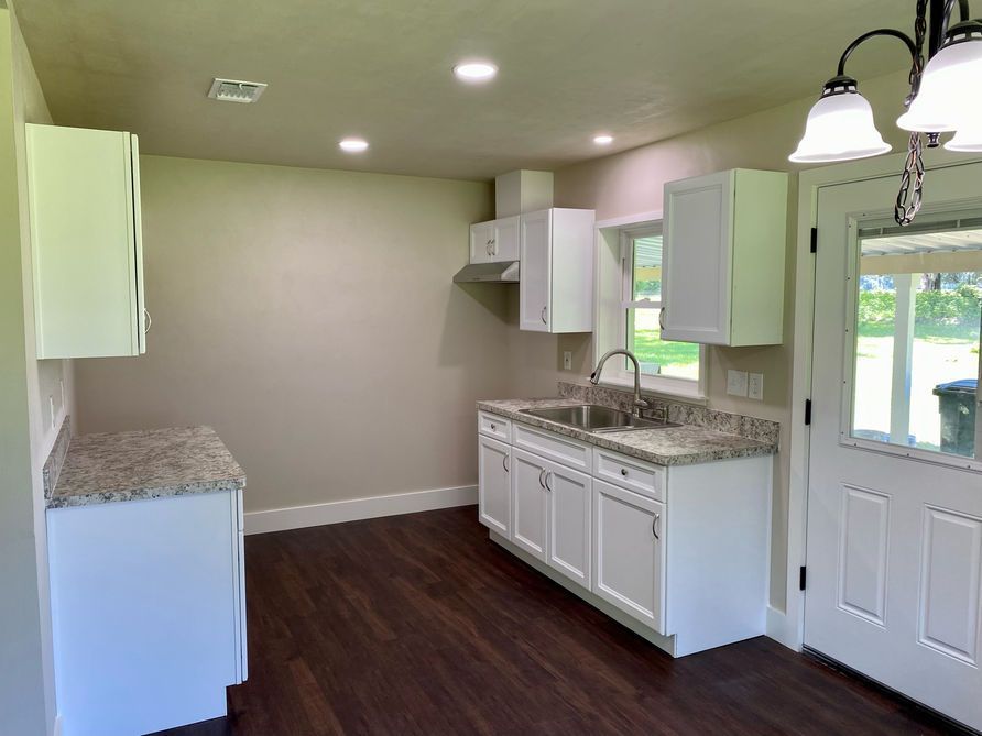 Kitchen with white cabinets, gray countertops, and dark wood floors.