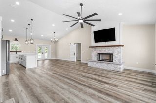 Open-concept living space with gray flooring, vaulted ceiling, fireplace, and kitchen island.
