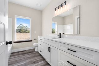 Modern bathroom with white vanity, black hardware, gray floor, and a window.