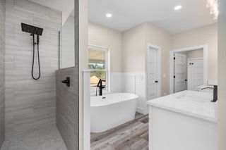 Modern bathroom with gray tiled shower, white tub, and vanity.