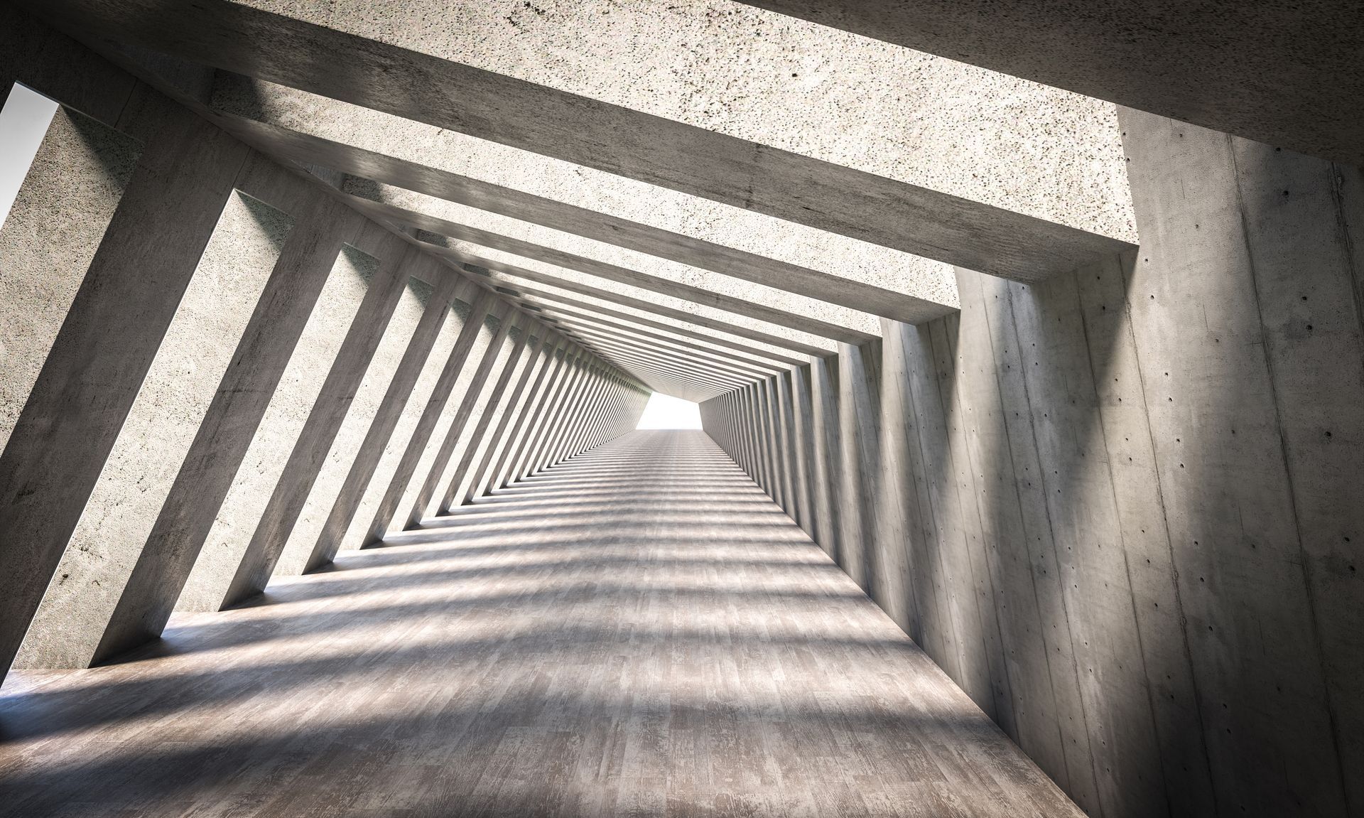 Concrete tunnel with angled supports, leading to light at the end.