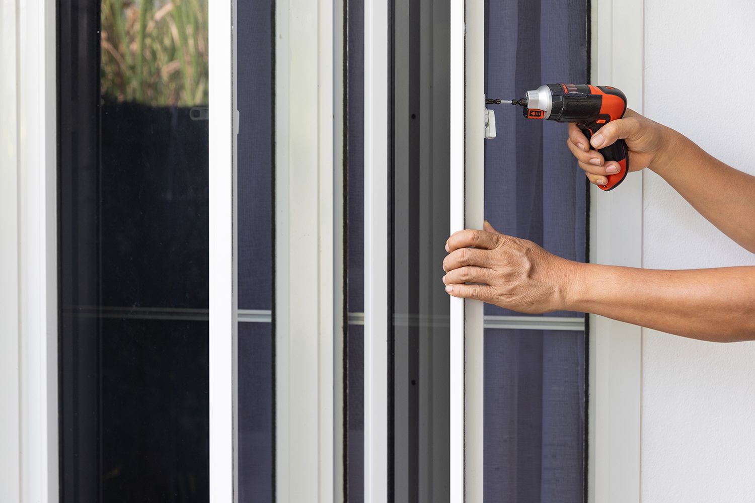 Close-up of a handyman repairing a white window handle with a cordless electric screwdriver. Close-up of a handyman repairing a white window handle with a cordless electric screwdriver.