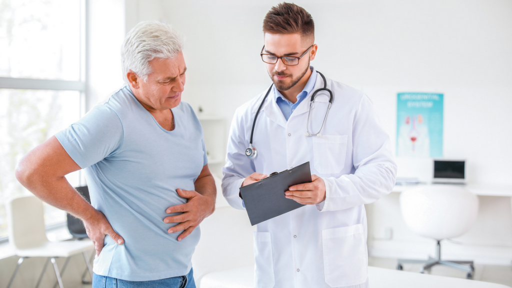 A doctor is talking to a patient who is holding his stomach.