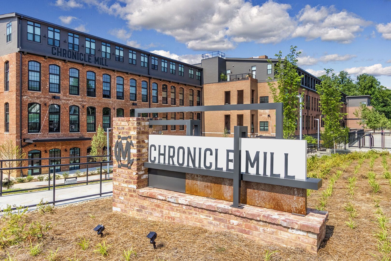 Exterior brick building with a Chronicle Mill sign and landscaped entrance.