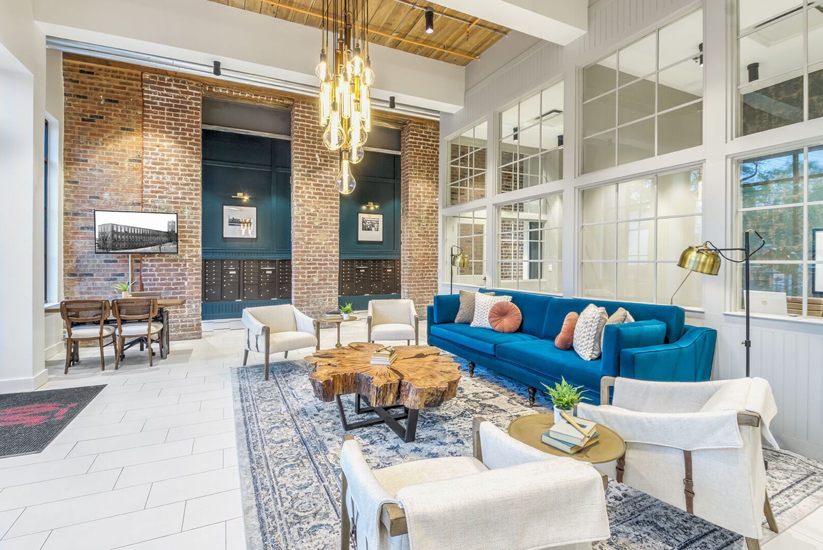 Bright modern apartment community lounge with brick walls, blue sofa, and glass partitions.