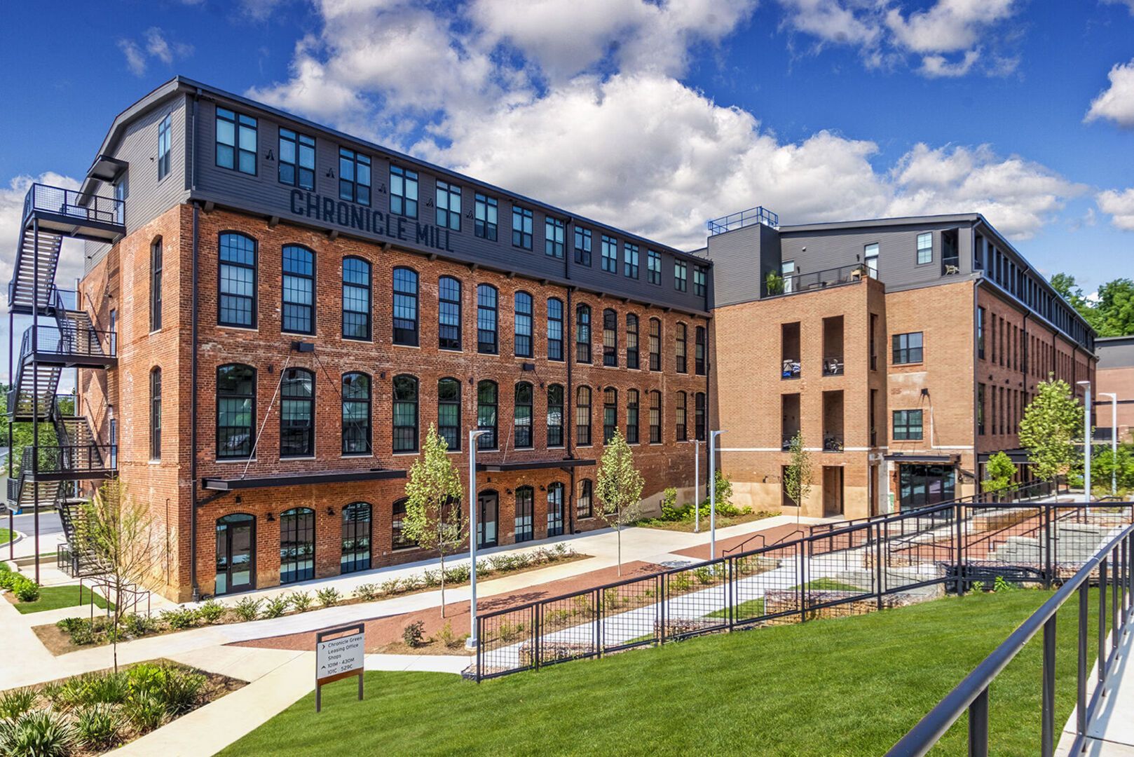Exterior view of Chronicle Mill apartment complex with brick buildings, windows and landscaped walkways.