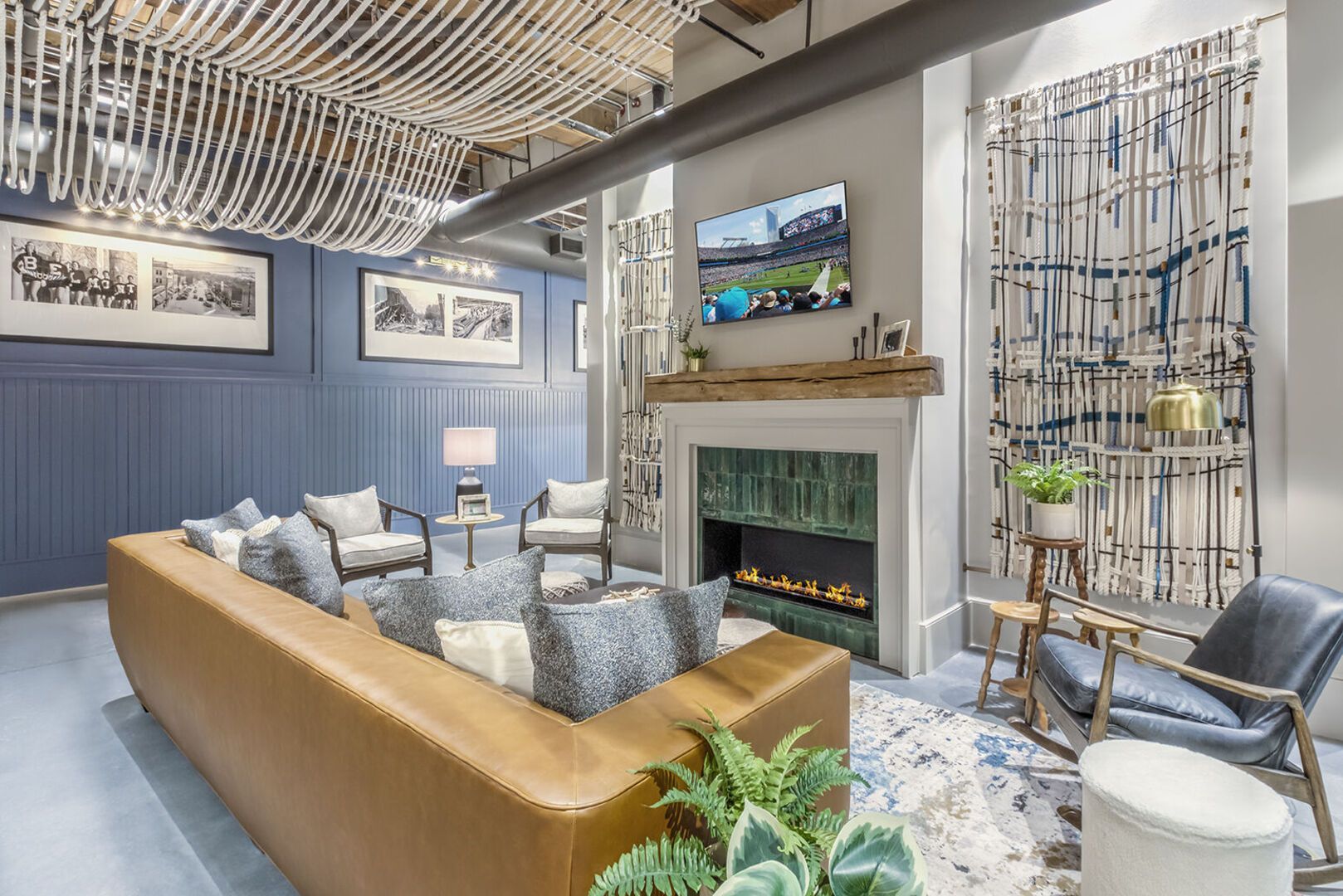 Interior community lounge with a fireplace, wall-mounted TV, and comfortable seating.