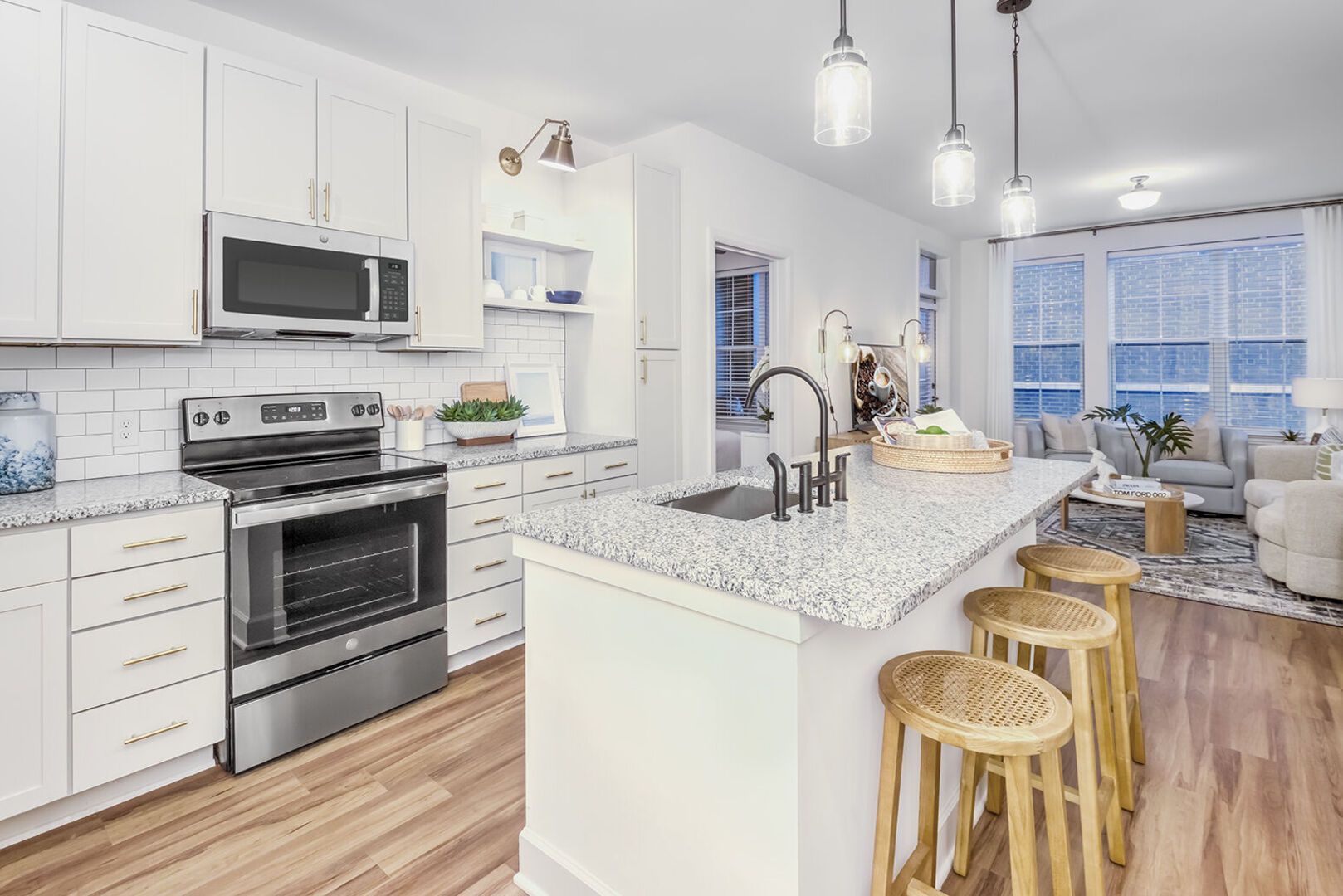 Bright modern kitchen with white cabinets, granite island, and stainless steel appliances.