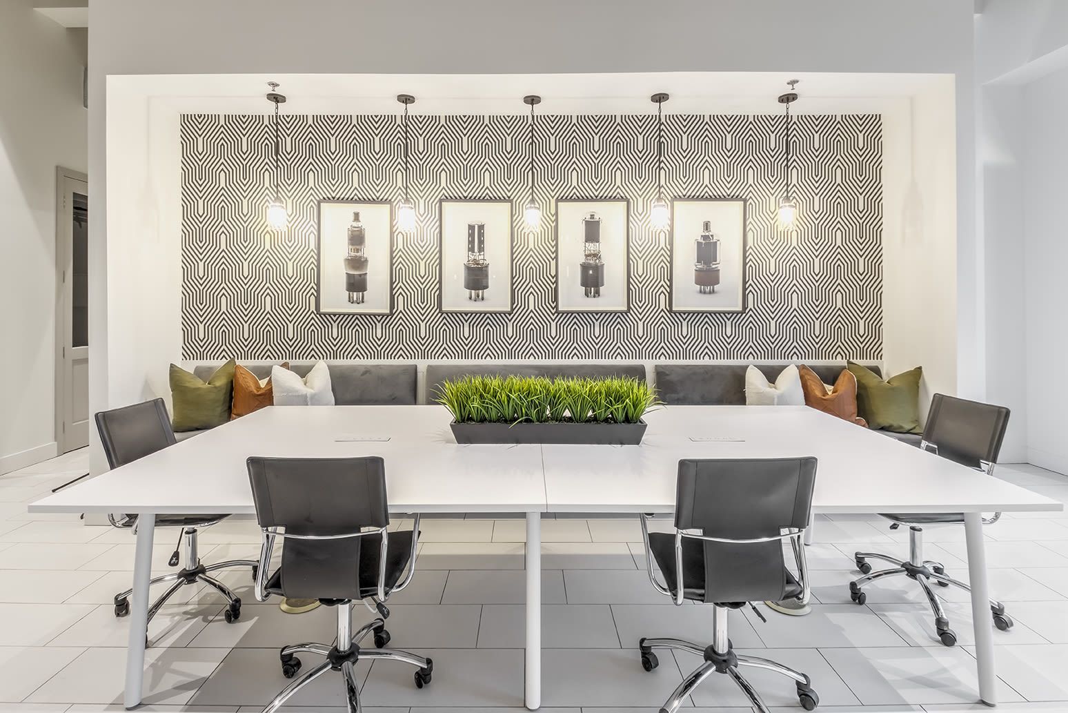 Modern conference room with a large white table, black swivel chairs, and a patterned accent wall.