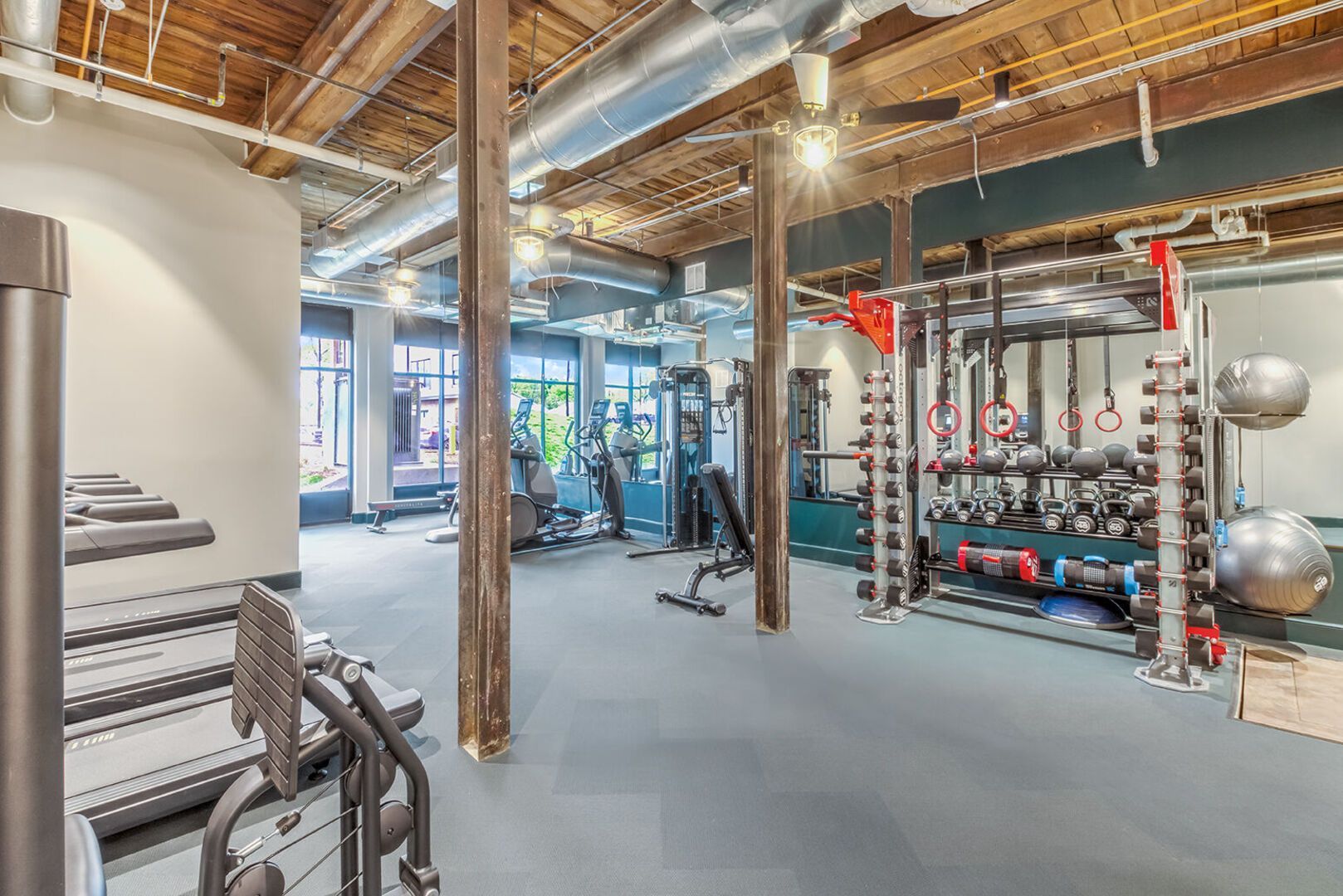 Interior view of a modern multifamily gym with treadmills, weights, and circuit training stations.