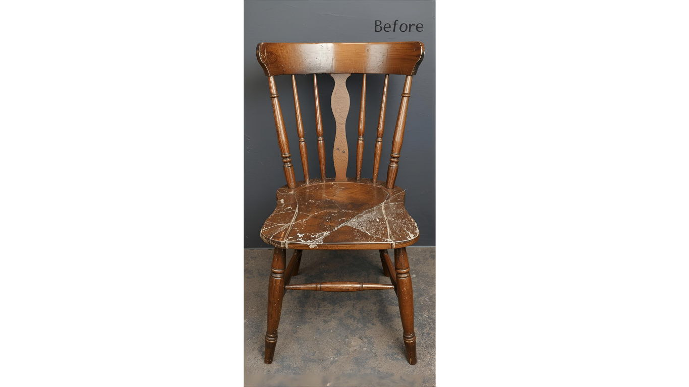 A worn wooden chair, with a curved back, spindles, and a distressed seat, stands against a gray background.