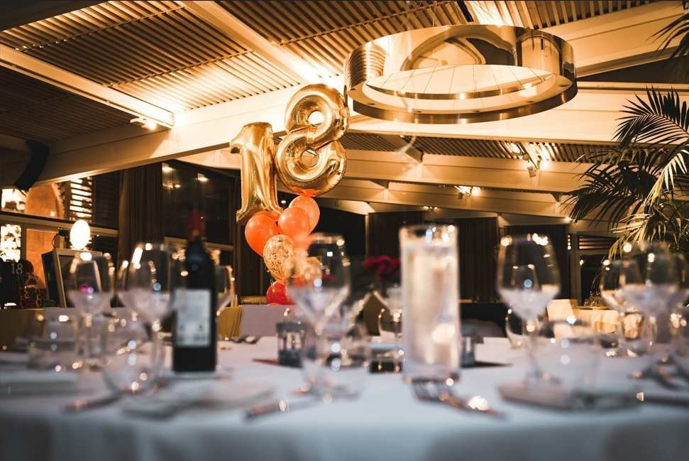 A table set for a birthday party with balloons and wine glasses.