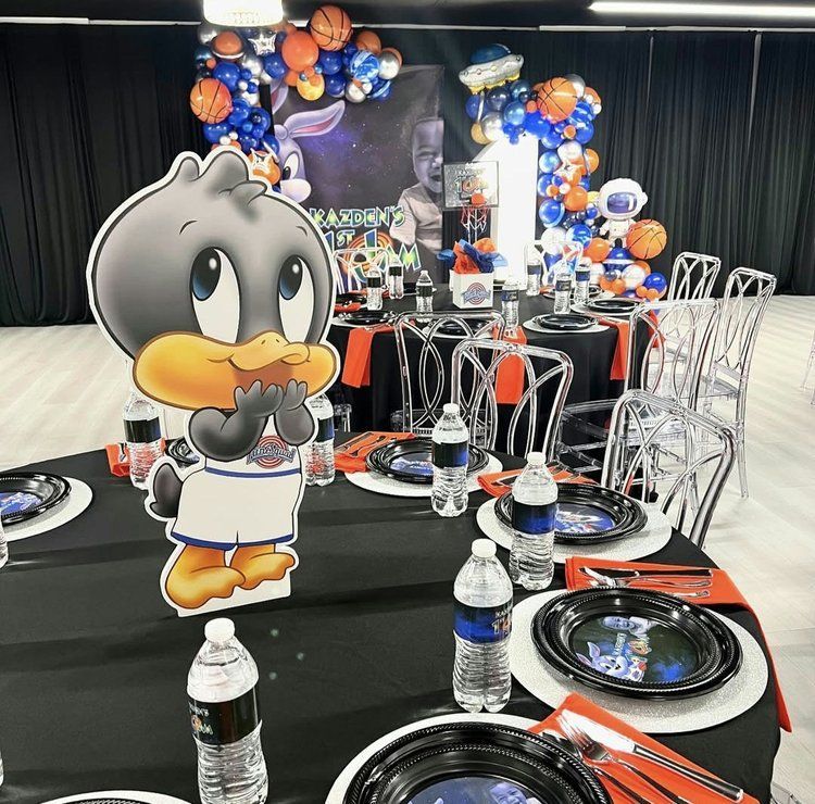 A table with plates , water bottles , and a duck on it.