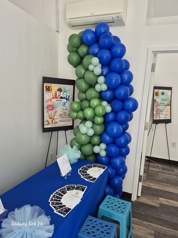 A room filled with blue and green balloons and a table