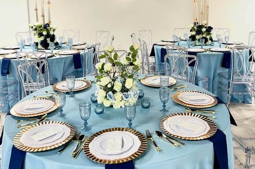 A table with plates , utensils , and a vase of flowers on it.