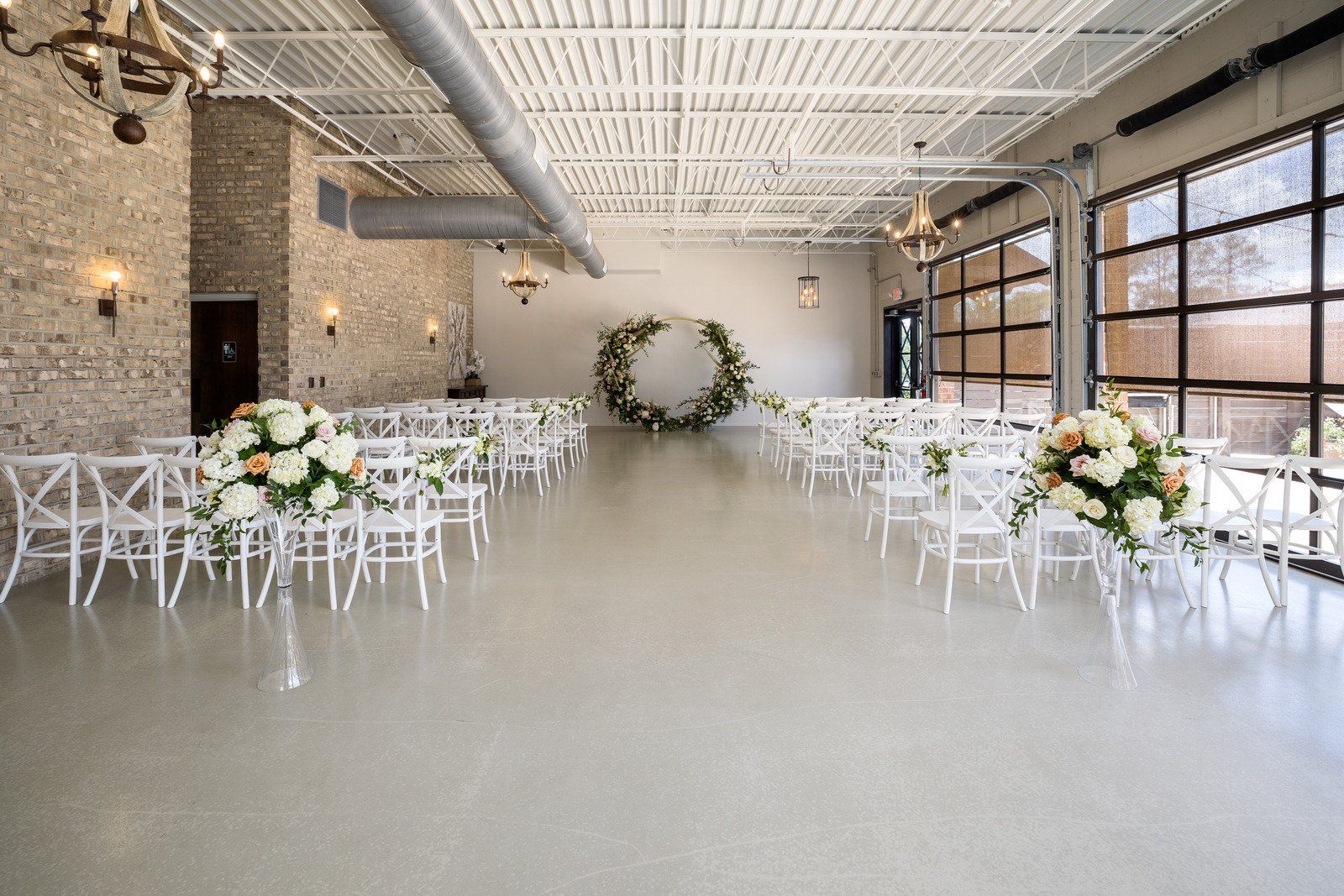 A large room with white chairs and flowers on the floor.