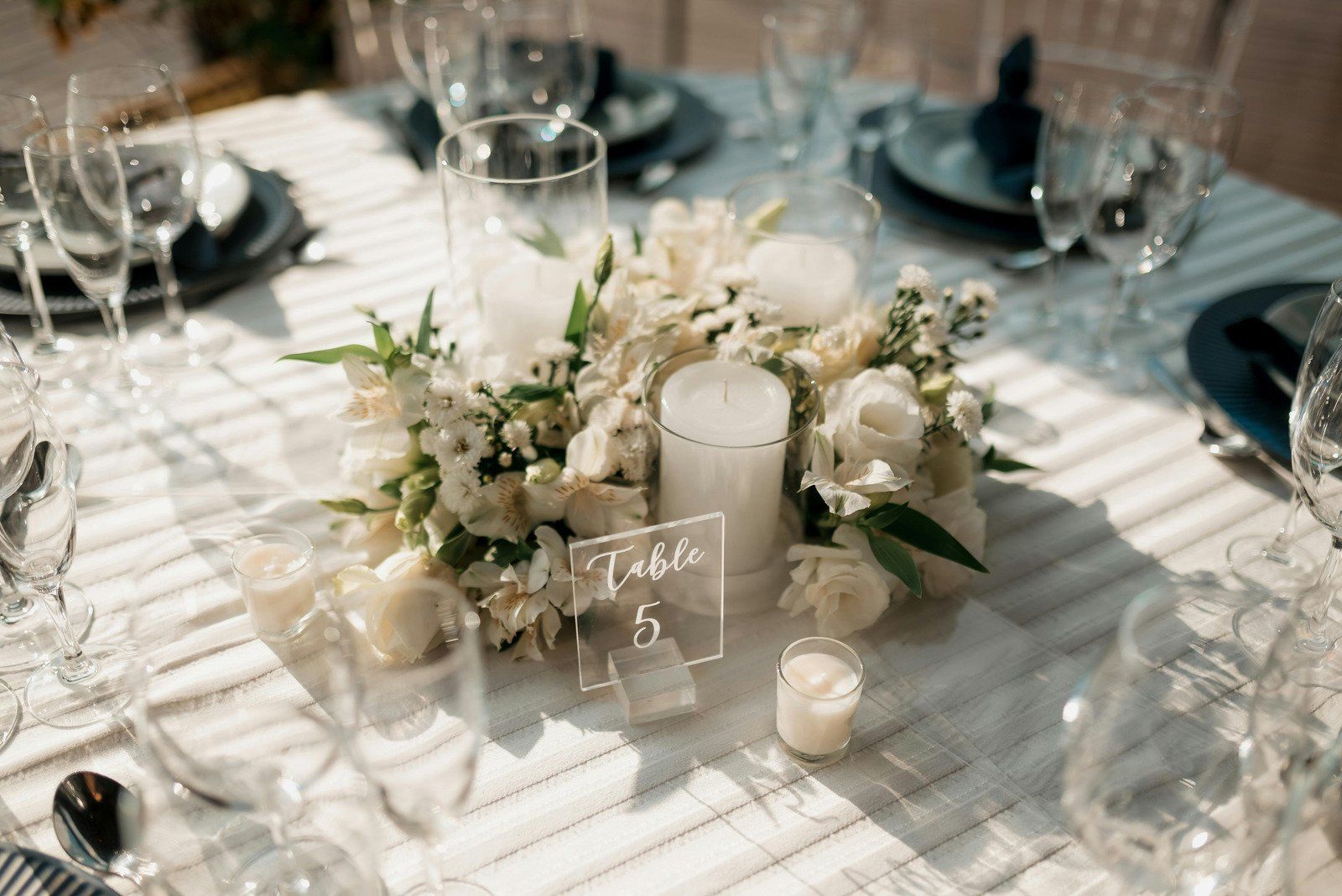 A table set for a wedding reception with a centerpiece of white flowers and candles.