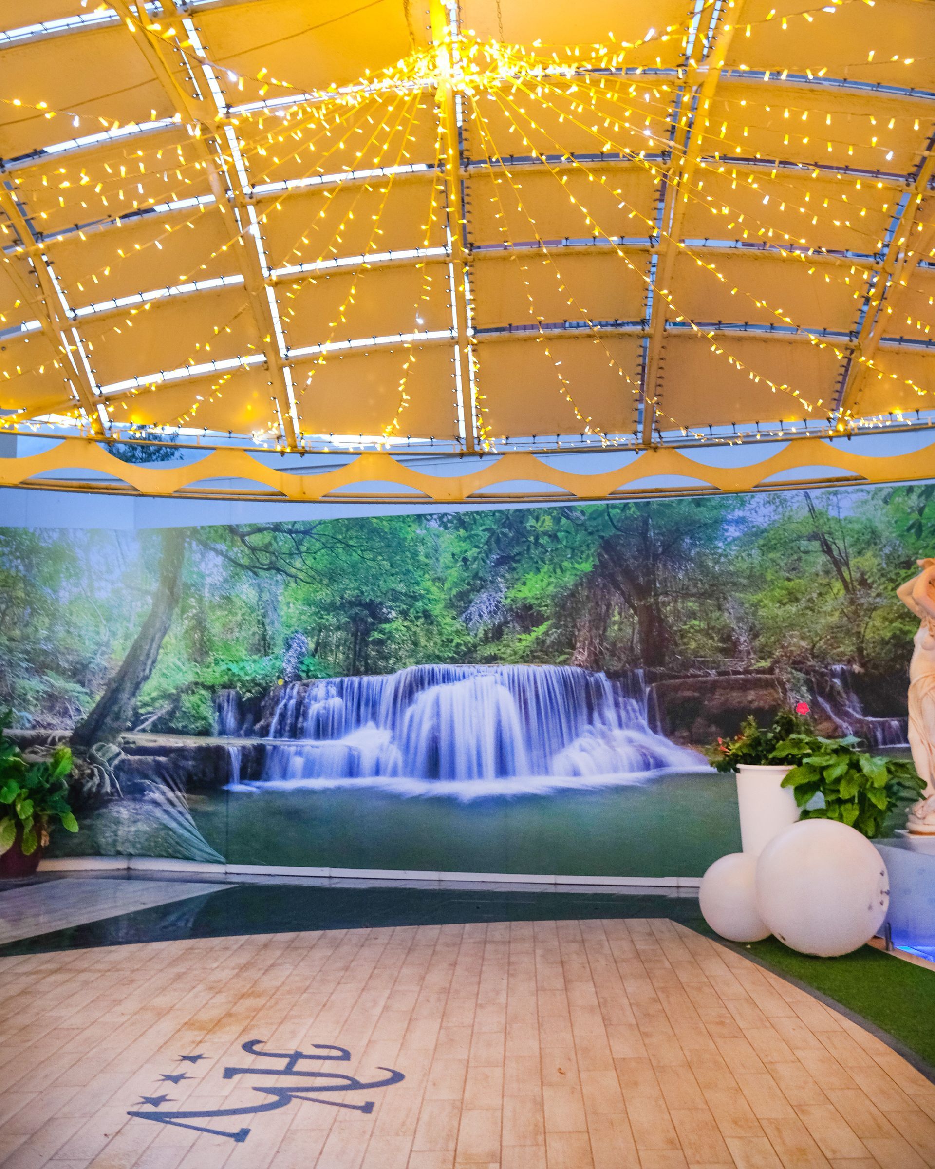 Struttura con tetto giallo, sullo sfondo una cascata e pavimento in legno.