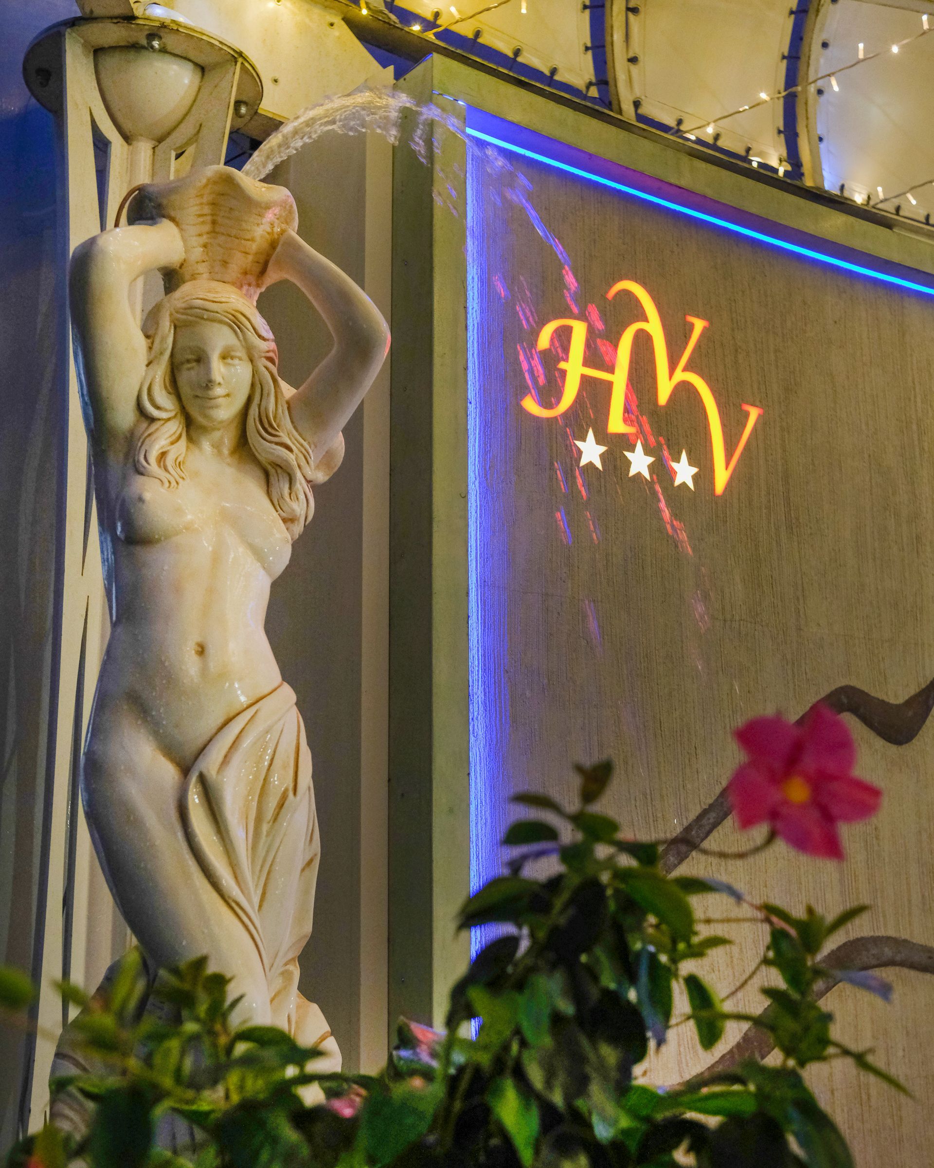 Statua di una donna che versa acqua, accanto a un cartello con le lettere