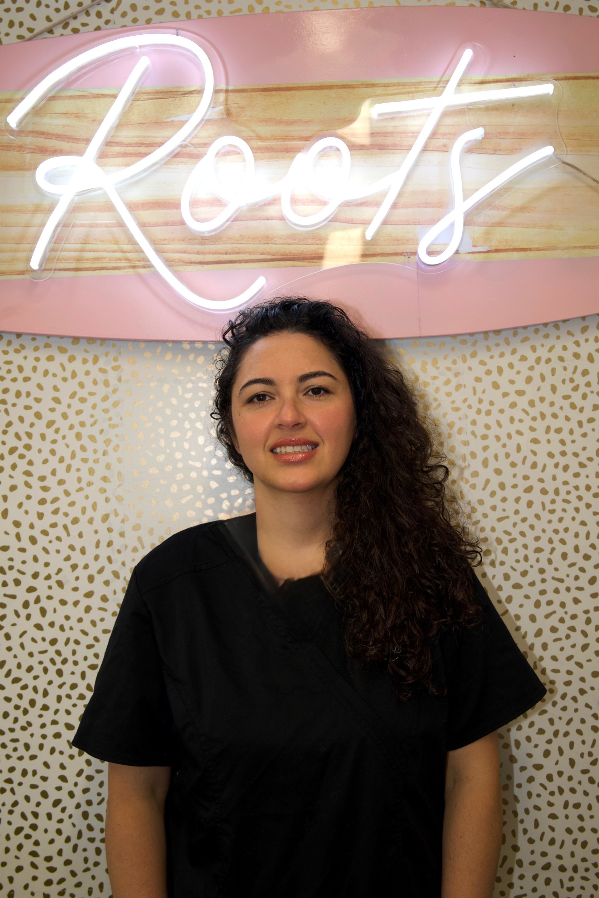 A woman wearing a black scrub top with the word ross on it