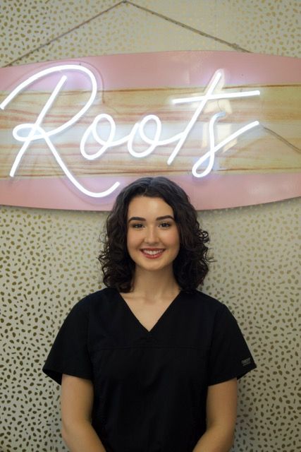 Woman in black scrubs smiling in front of a 