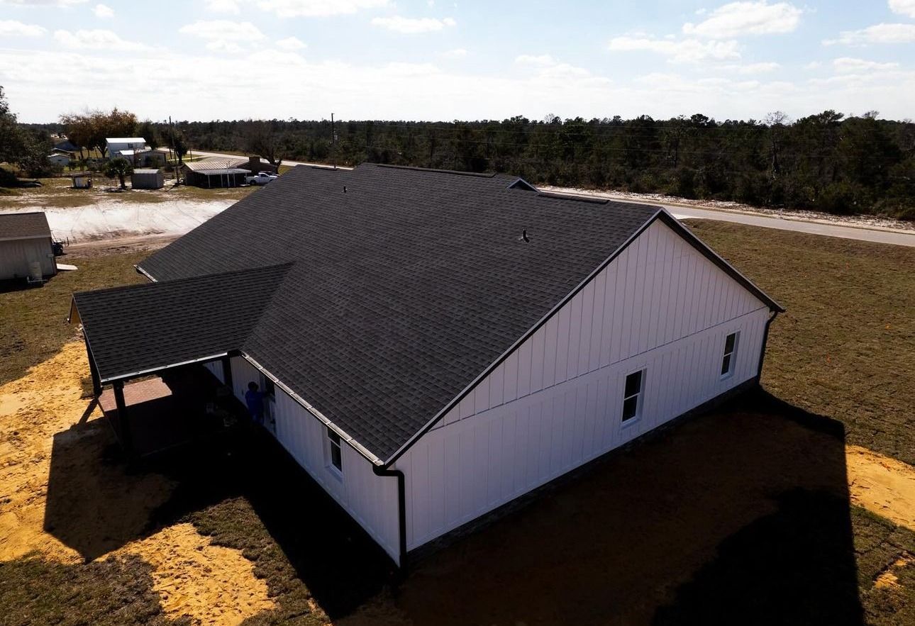An aerial view of a white house with a black roof.