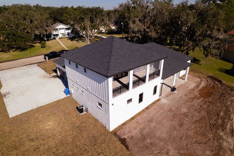 An aerial view of a white house with a black roof