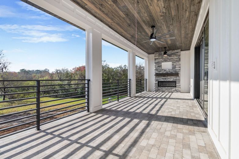 A large covered porch with a ceiling fan and a fireplace.