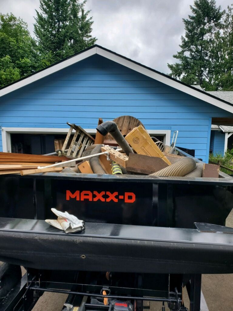 Truck bed filled with debris, in front of a blue house.  
