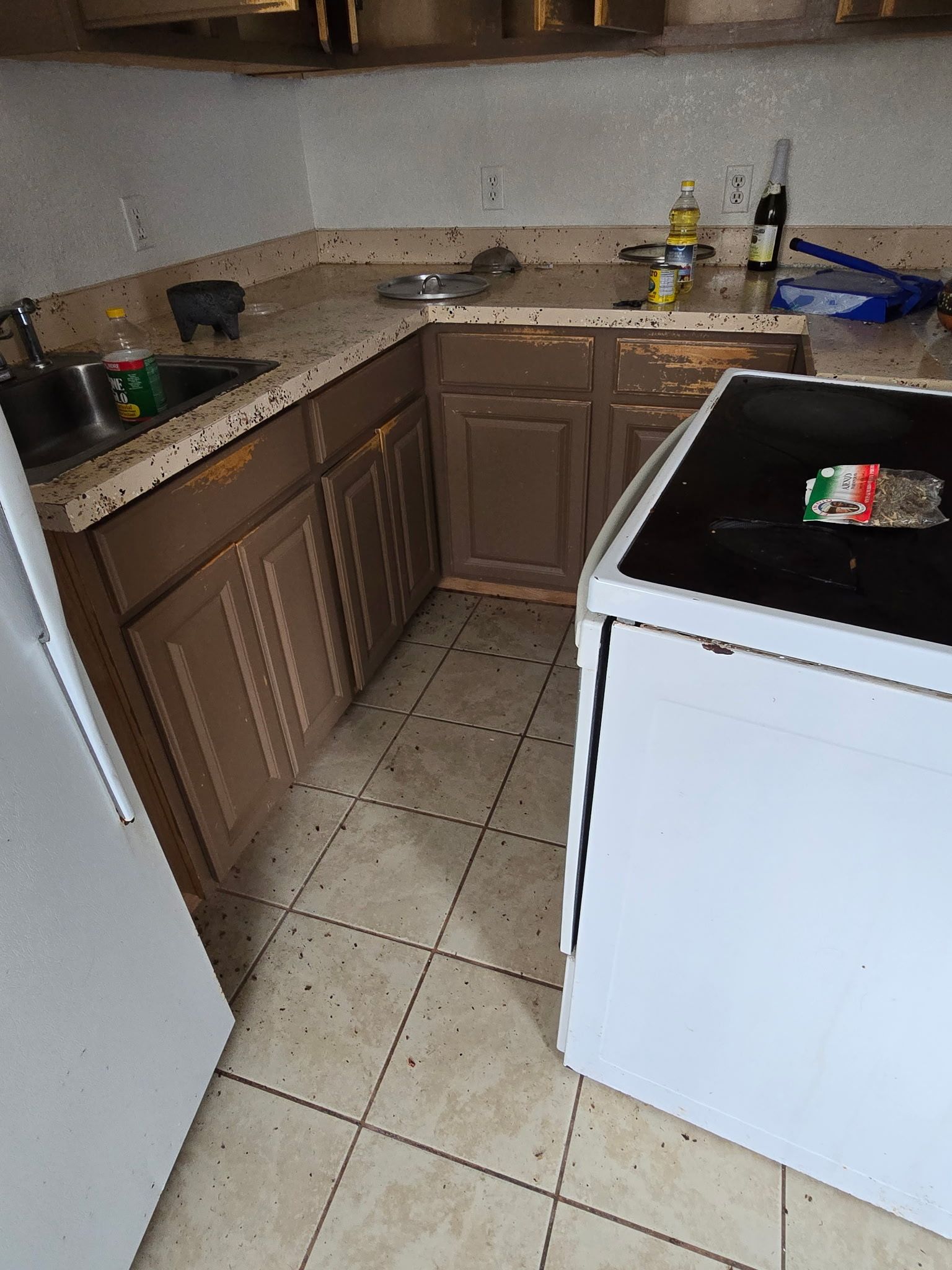 Kitchen with brown cabinets, tan countertops, and a white stove. The floor is tiled.