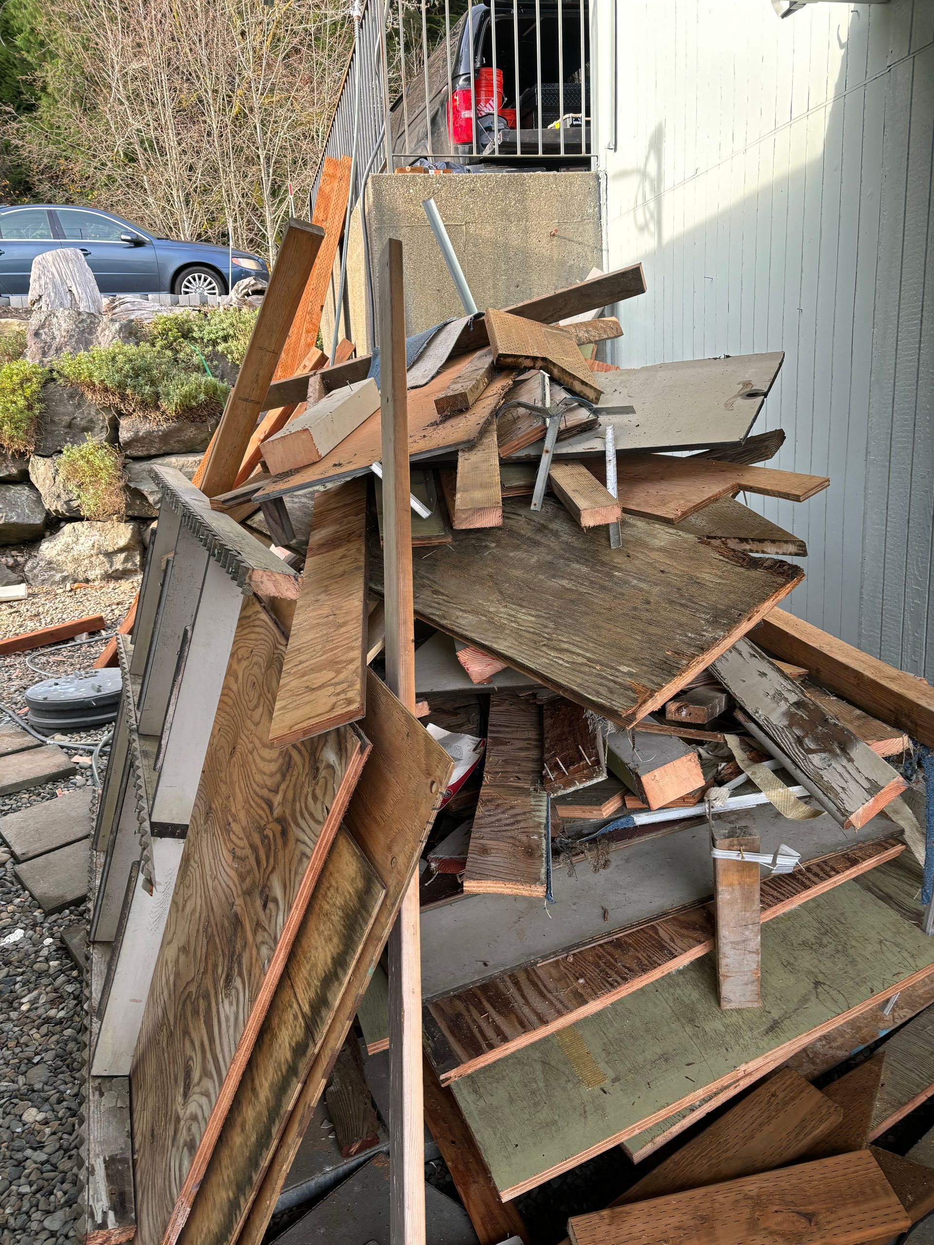 Pile of torn up wood debris against a building, likely from a demolition or construction project.